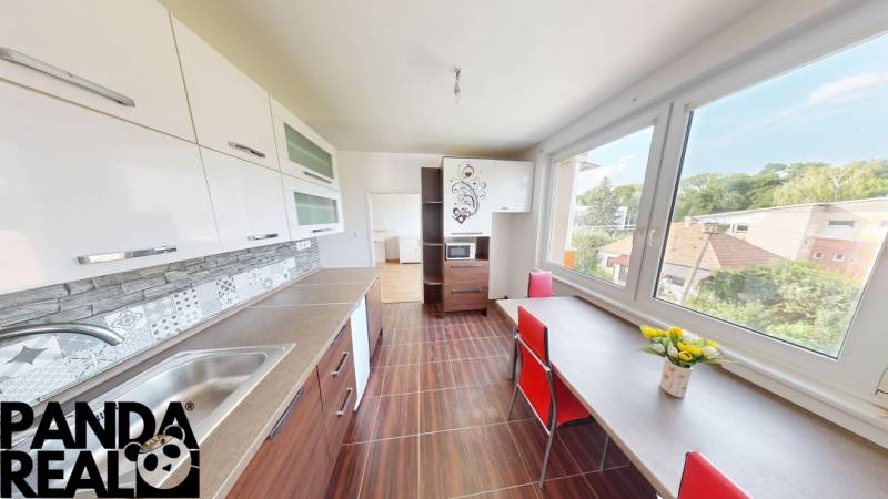 A kitchen in a 4-room apartment with a wooden decor floor, a large window, and white furniture.