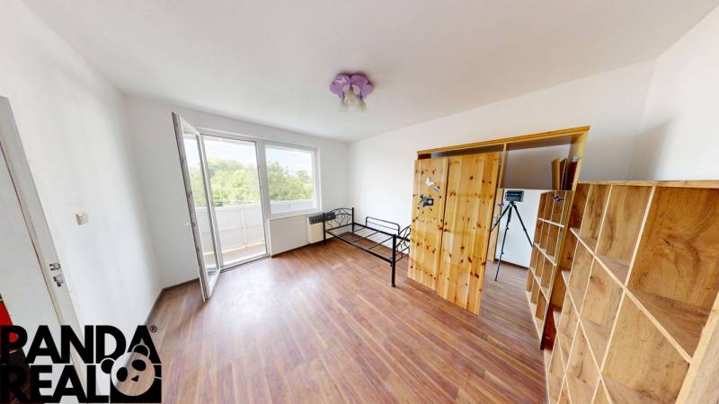 A spacious room with a wooden decor floor and access to a balcony in a 4-room apartment.
