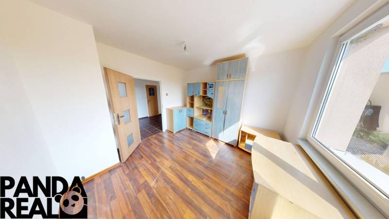 A room in a 4-room apartment, wooden decor flooring, built-in furniture, large window.