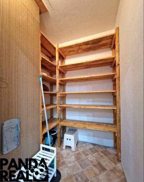 A pantry in a 4-room apartment with wooden shelves and tiled flooring.