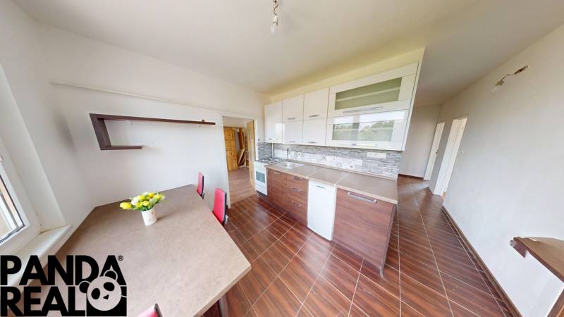 The kitchen of a 4-room apartment with a wooden decor floor, a dining table, and cabinets.