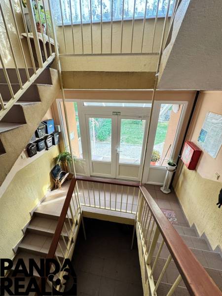 Staircase in a 4-room apartment with a bright hallway, railing, and a view of the exterior.