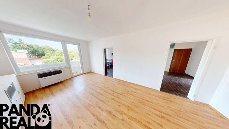 A spacious living room with light-colored walls and a wooden decor floor in a 4-room apartment.