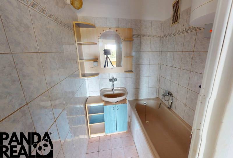 A bathroom in a 4-room apartment with a bathtub, sink, and cabinet.