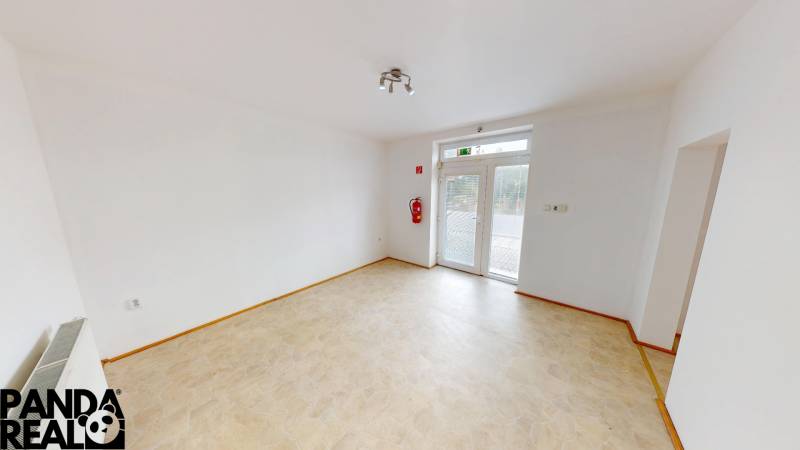 Interior of a family house with white walls, a French window, and a cream floor.
