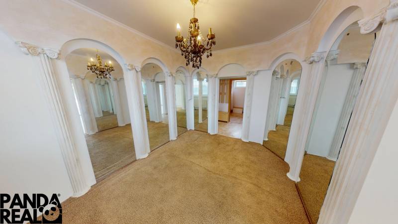 Interior of a family house with arched mirrors, chandelier, and carpet.