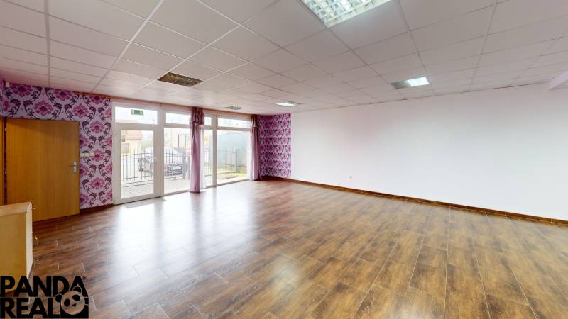 A spacious room in a family house with a wooden decor floor and floral wallpaper.