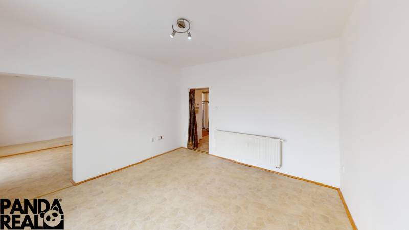 A room in a family house with white walls, a heating unit, and two doors.
