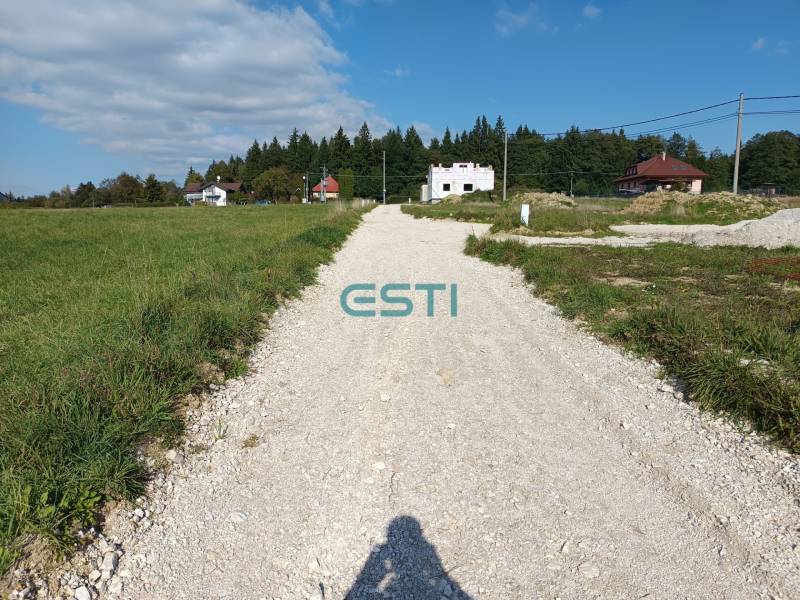 The road on Stránska Street with residential plots, surrounded by houses and greenery.