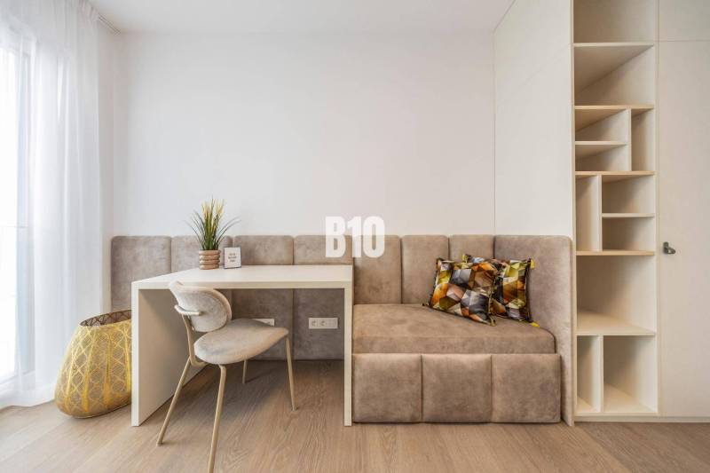 A workspace with a chair, table, bench, and shelves in a 3-room apartment.