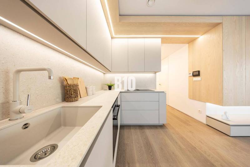 A kitchen in a 3-room apartment with a wooden decor floor and minimalist design.