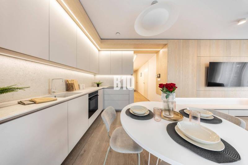 Stylish kitchen in a 3-room apartment with wood-patterned flooring and modern furniture.