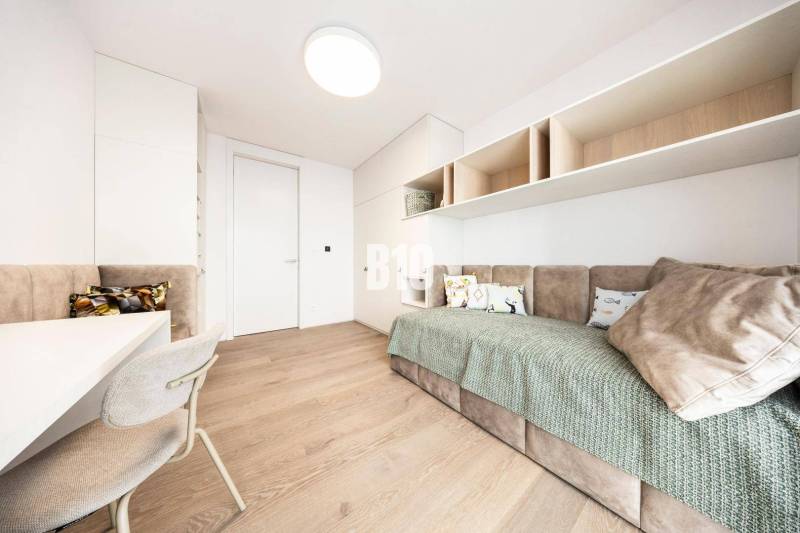 A minimalist room with a sofa, light furniture, and a wooden decor floor in a three-room apartment.