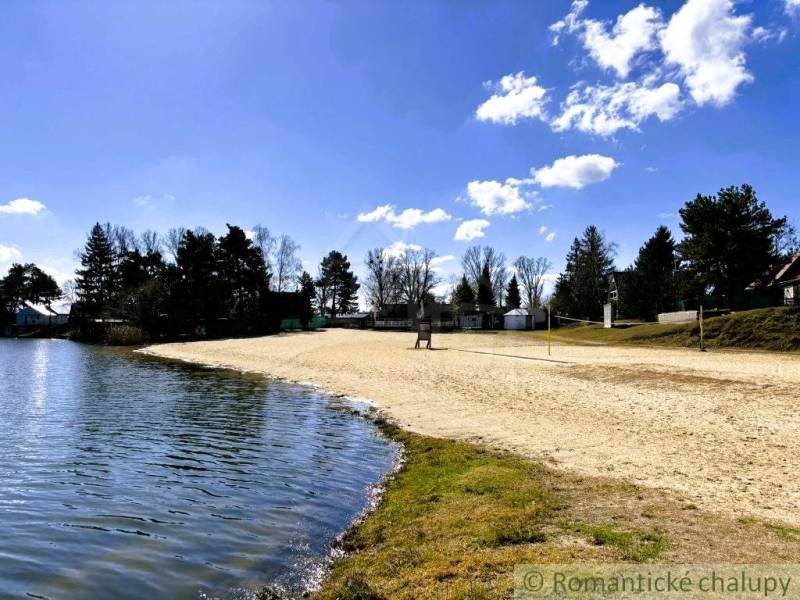 The beach near the cottage in Malé Leváre surrounded by greenery and a blue sky.