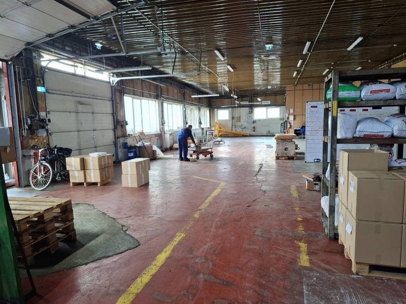 Interior of warehouses and halls with pallets, boxes, and stored materials.