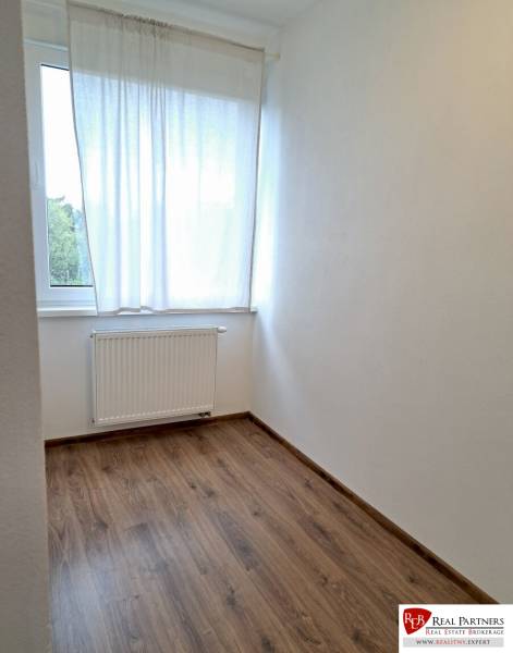 A simple room in a 3-room apartment with a wooden decor floor.