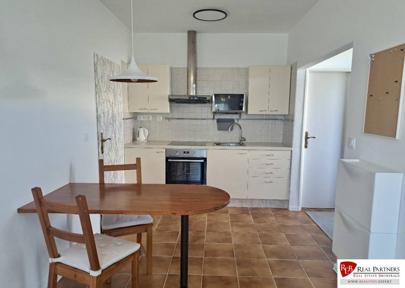 A kitchen in a 3-room apartment with a ceramic floor, a table, and chairs.