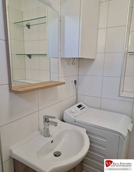 A bathroom in a 3-room apartment with a sink, cabinet, and washing machine.