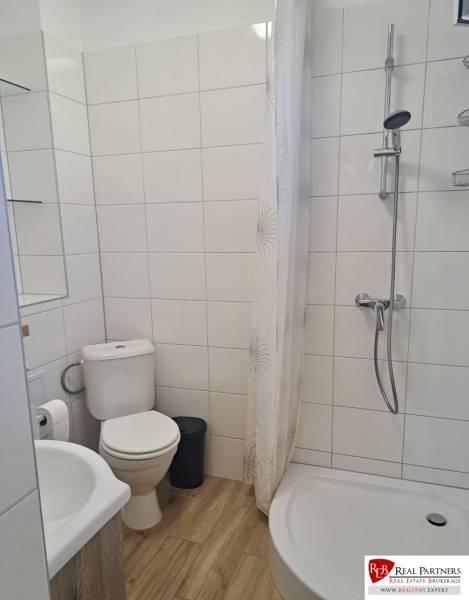 Bathroom in a 3-room apartment with a bathtub, shower, and tiles with a wooden decor.