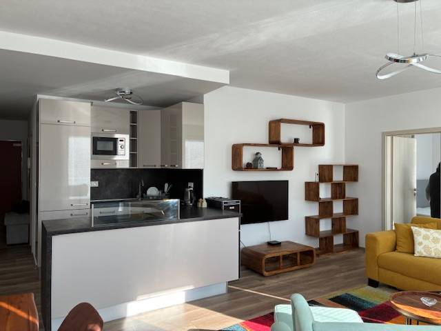 Living room in a 3-room apartment with a kitchenette, yellow sofa, and wooden decor.