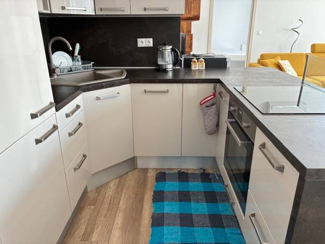 A kitchen in a 3-room apartment with a kitchen unit, sink, and floor with a wooden decor.