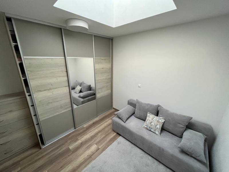 A wardrobe with sliding doors and a sofa, a floor with a wooden decor in a 2-room apartment.