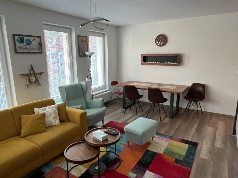Bright living room in a 2-room apartment with a sofa, armchair, and wooden decor on the floor.