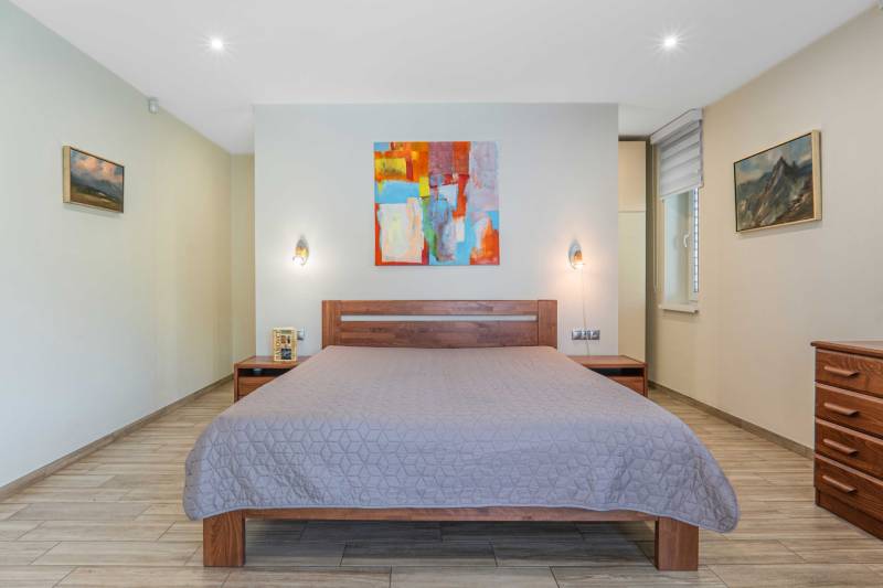 A bedroom in a family house with a wooden decor floor and an abstract painting.