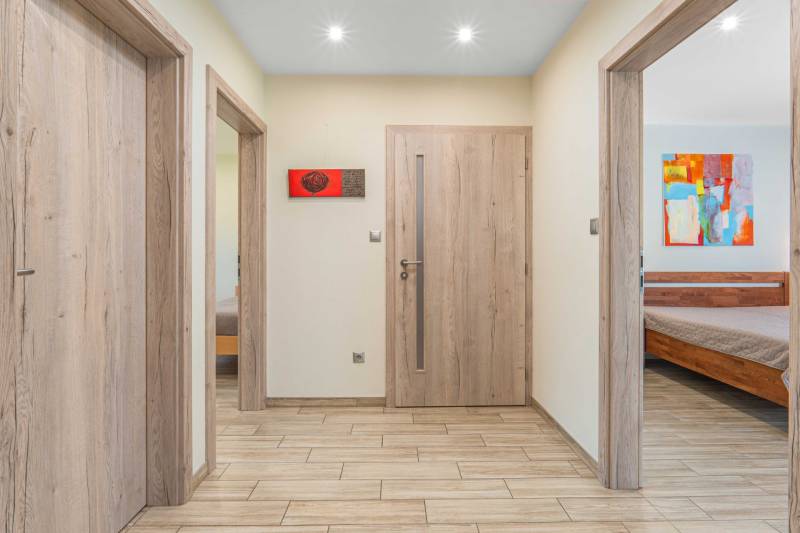 Hallway of a family house with wooden doors, a painting, and entrances to rooms.