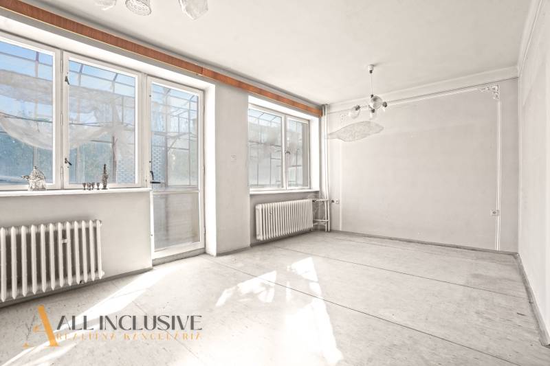An empty room with large windows and radiators in a family house.