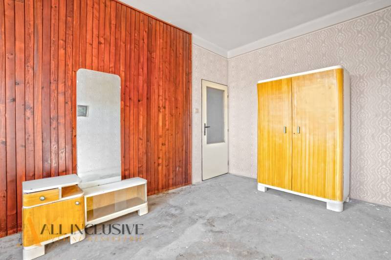 An older interior with wooden paneling, a wardrobe, and a mirror in a family house.
