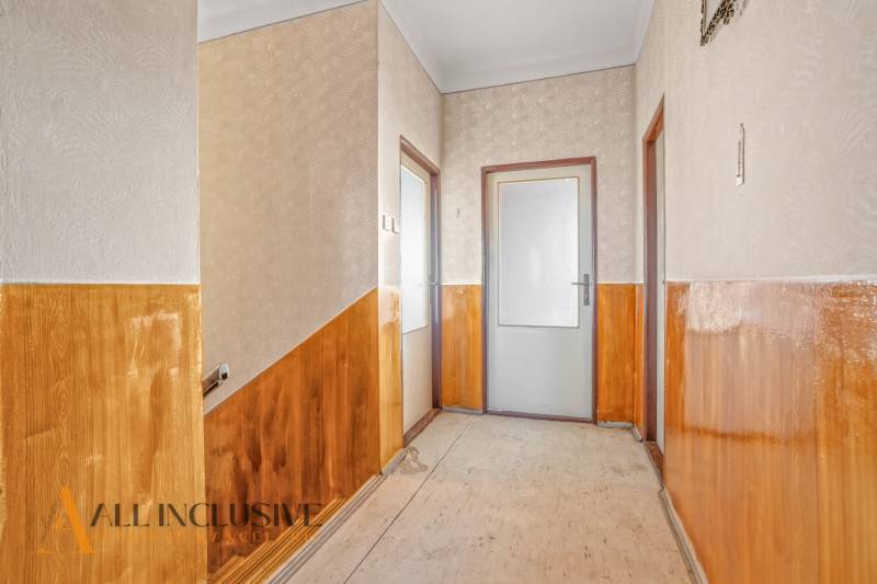 A hallway in a family house with wood paneling and textured walls.