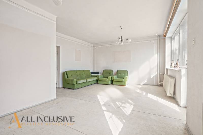 Living room in a family house with three green sofas and large windows.