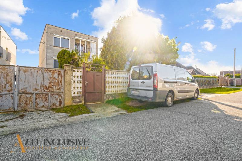 A family house in Veľká Mača with a car on the driveway and sunny weather.