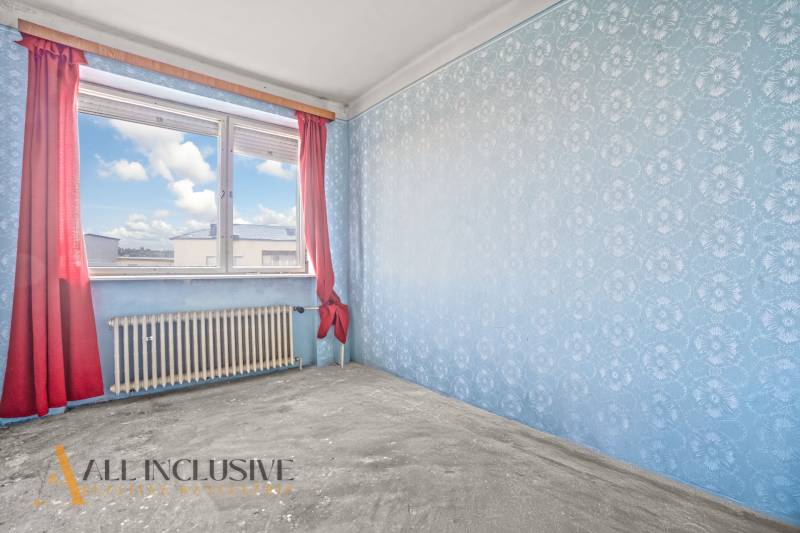 A room in a family house with blue wallpaper and red curtains on the window.
