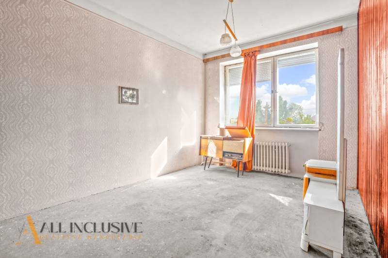 A room in a family house with wallpaper, a desk, and orange curtains.