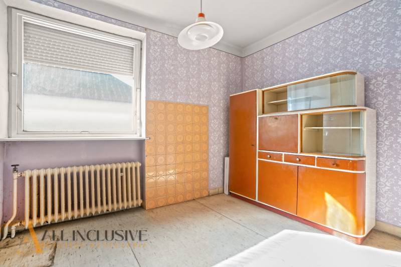 Vintage wardrobe with decorative wallpaper and radiator in the interior of a family house.