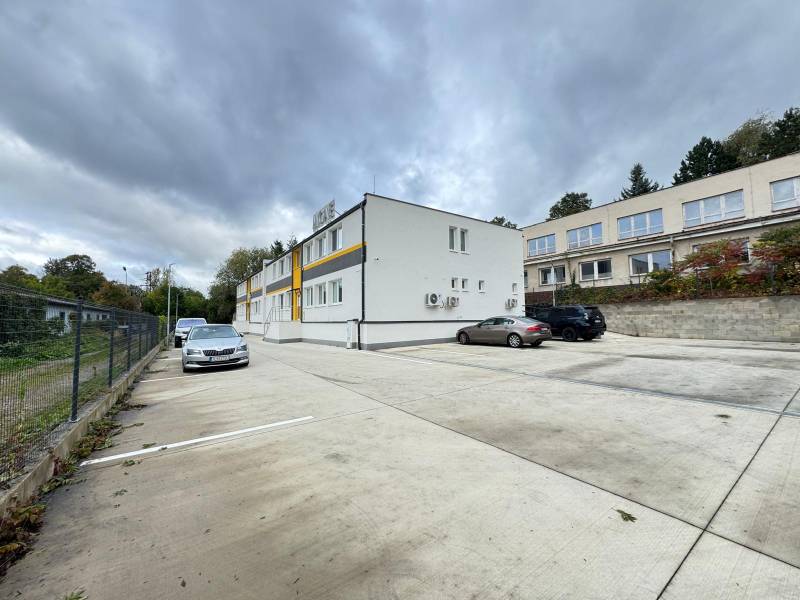 A parking lot in front of the offices in Dubnica nad Váhom surrounded by buildings and parked cars.