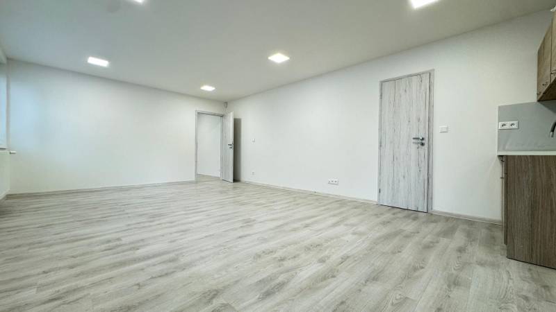 A spacious office with white walls and a floor with a wood decor.