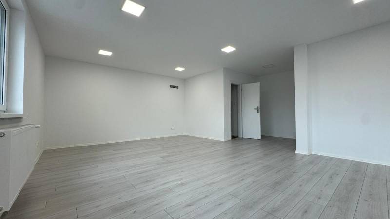 Empty offices with wood-patterned flooring and white walls.