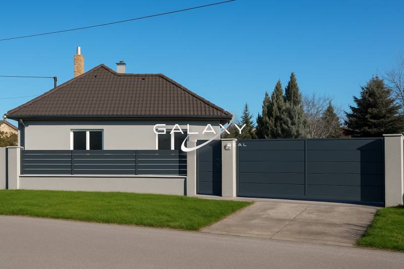 A family house in Horné Saliby with a flat roof, a fence, and a landscaped lawn.
