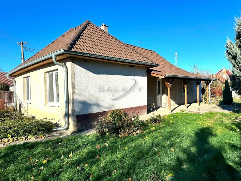 A family house in Horné Saliby with a pyramid roof stands in a green garden.