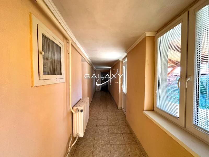 Hallway in a family house with a tiled floor and windows with blinds.