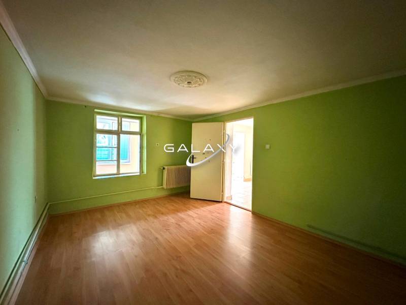 A room in a family house with green walls and a wood-patterned floor.