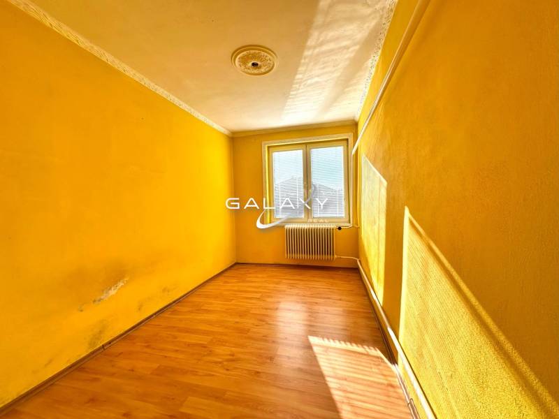 A room with a wooden floor and yellow walls in a family house.