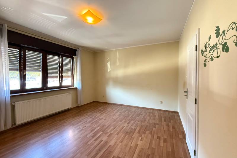 A spacious room in a family house with a wooden decor floor and a large window.