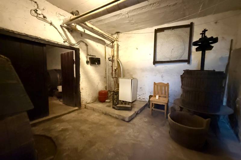 A basement in a family house with a boiler, technical equipment, and a wooden press.