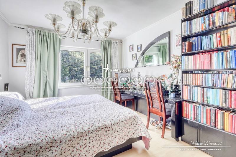 A bedroom in a family house with a bookshelf, chandelier, and large mirror.