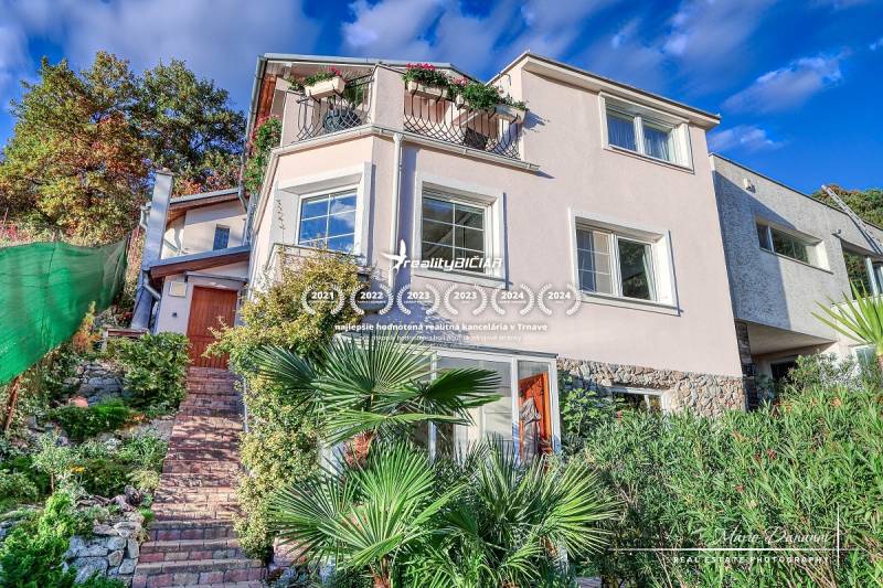 A family house on a street in Bratislava - Devín with an access garden path and plants.