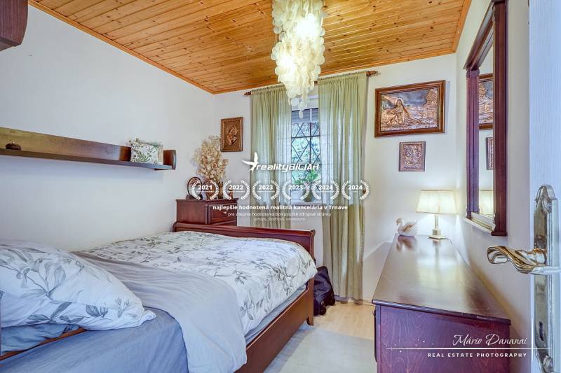 A bedroom in a family house with a wooden ceiling, chandeliers, and decorated walls.